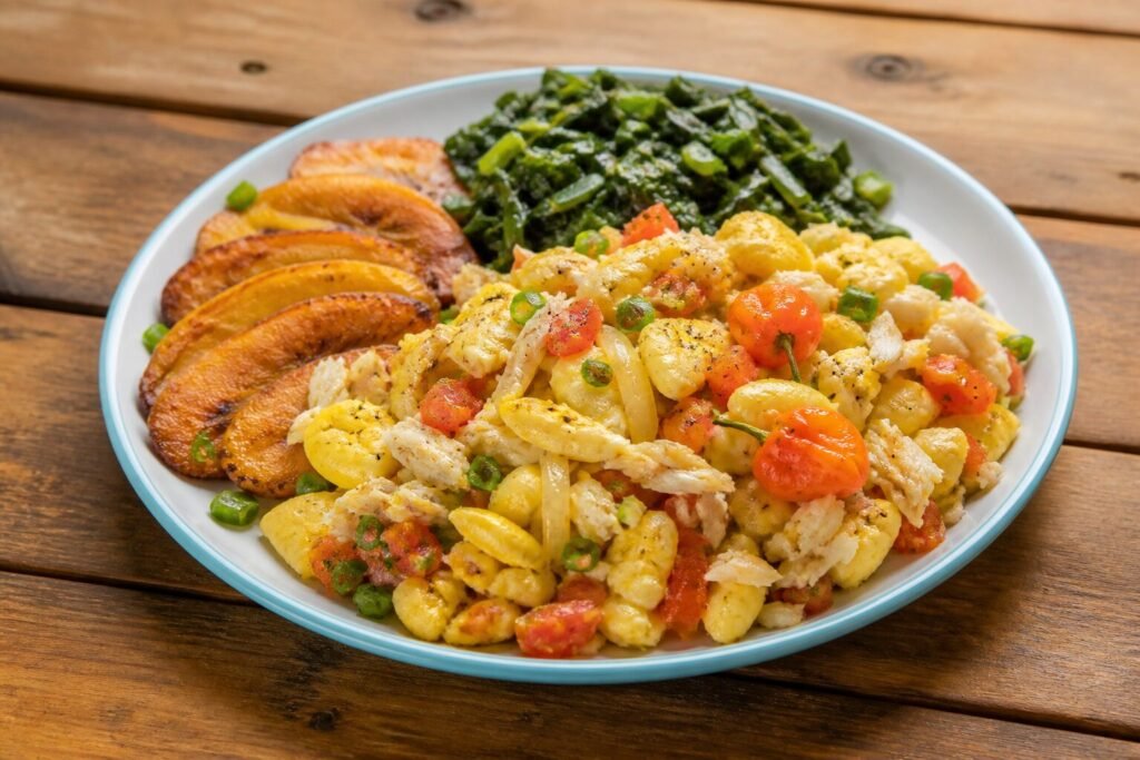 Jamaican ackee and saltfish with tomatoes, peppers, scallions, fried plantain, and greens.