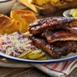 American barbecue pork ribs with smoky glaze, coleslaw, cornbread, and pickles.