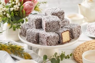 Chocolate-coated Australian lamingtons covered in coconut on a cake stand.