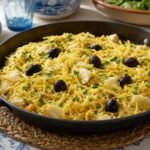 Portuguese bacalhau a Bras with flaky cod, crisp potato matchsticks, scrambled egg, black olives, and parsley.