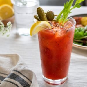 A classic Bloody Mary in a chilled glass with celery, lemon, cracked pepper, and ice on a brunch table.