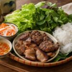 Vietnamese bun cha with grilled pork, rice noodles, herbs, pickled vegetables, and nuoc cham.