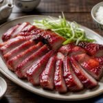 Glossy slices of Chinese char siu pork served with scallions and steamed rice.