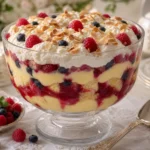 Classic British trifle layered with sponge cake, berries, custard, whipped cream, raspberry jam, and toasted almonds.