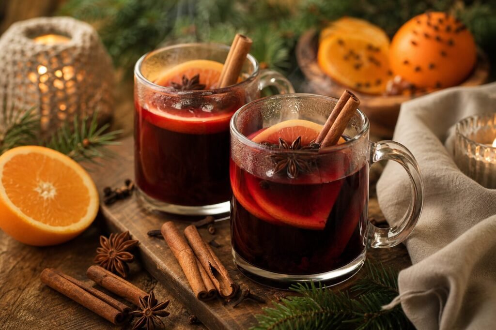 Steaming ruby-red mulled wine with orange slices, cinnamon, star anise, and cloves in clear mugs.