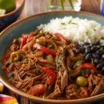 Cuban ropa vieja with tender shredded beef, tomato and pepper sauce, olives, white rice, black beans, and herbs.