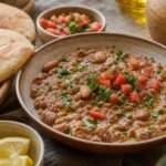 Creamy Egyptian ful medames with olive oil, cumin, lemon, parsley, tomatoes, and warm pita.