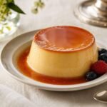 A glossy French creme caramel custard unmolded with amber caramel sauce and a few berries.