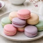 Pastel French macarons with smooth shells and creamy fillings on a dessert plate.