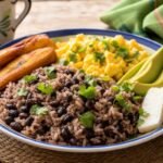 Costa Rican gallo pinto with black beans, rice, fried egg, plantain, avocado, cheese, and cilantro.