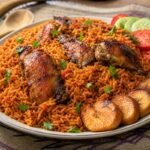 Ghanaian jollof rice with tomato-pepper rice, chicken, golden fried plantain, vegetables, and herbs.