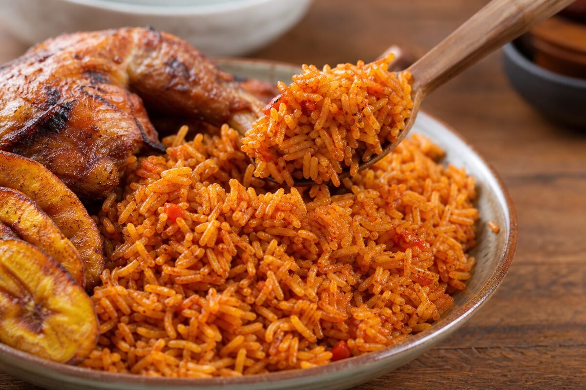 Close serving of Ghanaian jollof rice with rich tomato rice, tender chicken, and golden fried plantain.