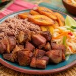Haitian griot with crisp pork, bright pikliz, golden fried plantains, rice, and lime.