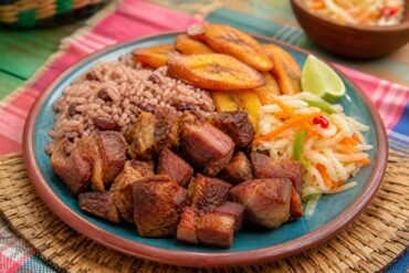 Haitian griot with crisp pork, bright pikliz, golden fried plantains, rice, and lime.