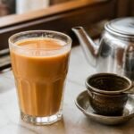 Hong Kong-style milk tea with smooth amber black tea, evaporated milk, and a traditional metal tea strainer.