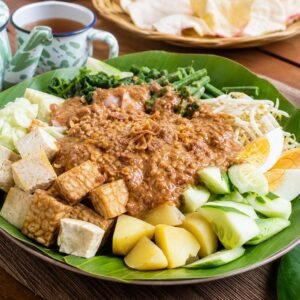 Indonesian gado-gado with blanched vegetables, tofu, tempeh, potatoes, egg, and peanut sauce.
