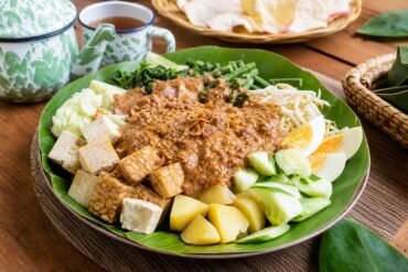 Indonesian gado-gado with blanched vegetables, tofu, tempeh, potatoes, egg, and peanut sauce.