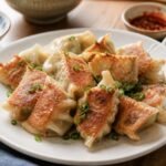 Pan-seared Chinese jiaozi dumplings with pleated wrappers and soy-vinegar dipping sauce.