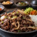 Glossy Korean bulgogi beef with onions, mushrooms, sesame seeds, scallions, and rice.