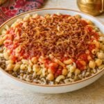 Egyptian koshari with rice, lentils, macaroni, chickpeas, tomato sauce, and crispy onions.