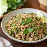 A bowl of Lao laap with minced meat, fresh herbs, toasted rice powder, and lime.