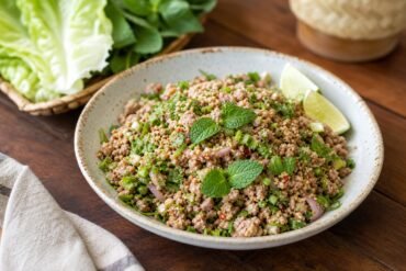 A bowl of Lao laap with minced meat, fresh herbs, toasted rice powder, and lime.