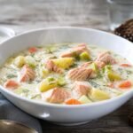 A bowl of Finnish Lohikeitto creamy salmon soup with potatoes, carrots, leeks, and dill.