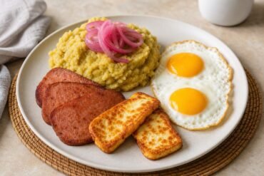Dominican mangu topped with pickled onions and served with fried salami, fried cheese, and eggs.