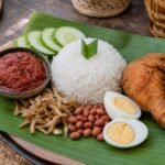 Malaysian nasi lemak with coconut rice, sambal, anchovies, peanuts, cucumber, egg, and fried chicken.