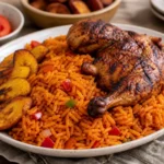A platter of Nigerian jollof rice with grilled chicken, fried plantains, tomatoes, and peppers.