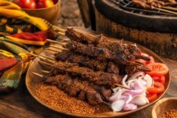 Smoky Nigerian suya beef skewers coated in spicy peanut seasoning with onions and tomatoes.