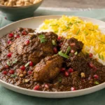 Persian chicken fesenjan in glossy walnut and pomegranate sauce with pomegranate arils, herbs, and saffron rice.