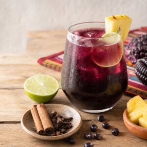 A chilled glass of Peruvian chicha morada with lime, pineapple, cinnamon, cloves, and purple corn.