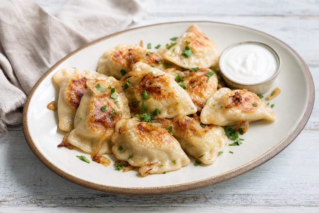 Polish pierogi ruskie with potato and cheese filling, caramelized onions, and sour cream.