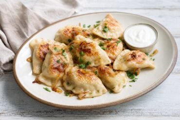 Polish pierogi ruskie with potato and cheese filling, caramelized onions, and sour cream.