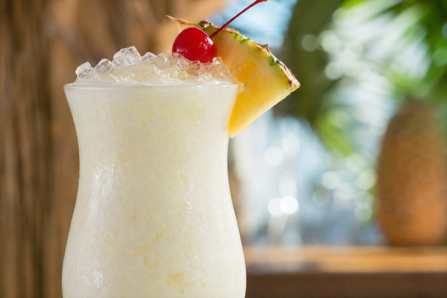 Close view of a chilled pina colada with creamy coconut-pineapple texture and fruit garnish.