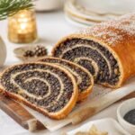 Sliced Polish makowiec poppy seed roll with a dense spiral filling and powdered sugar.