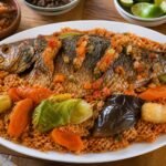 Senegalese thieboudienne with tomato rice, fish, carrots, cabbage, cassava, eggplant, and herbs.