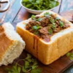A hollowed loaf of bread filled with spicy South African lamb curry and cilantro.