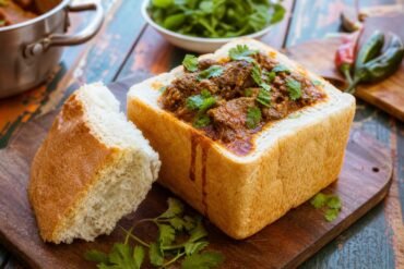 A hollowed loaf of bread filled with spicy South African lamb curry and cilantro.