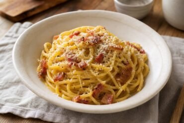 Fresh homemade spaghetti alla carbonara with silky Pecorino sauce, crisp guanciale, black pepper, and grated cheese.