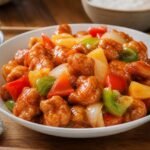Chinese sweet and sour pork with crisp battered pork, pineapple, bell peppers, onion, and glossy sauce.