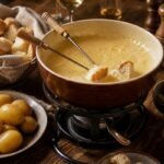 A bubbling Swiss cheese fondue with bread, potatoes, and pickles on a cozy Alpine table.