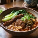 Taiwanese beef noodle soup with braised beef, wheat noodles, bok choy, scallions, and pickled mustard greens.