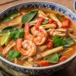Thai tom yum goong with shrimp, mushrooms, lemongrass, lime leaves, tomatoes, and cilantro.