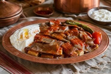 Turkish Iskender kebab with sliced lamb, toasted pide, tomato sauce, browned butter, and yogurt.