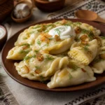 Ukrainian varenyky dumplings filled with potato and cheese, topped with caramelized onions, dill, and sour cream.