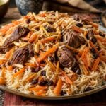 Afghan Kabuli Pulao with lamb, carrots, raisins, and almonds on a platter.