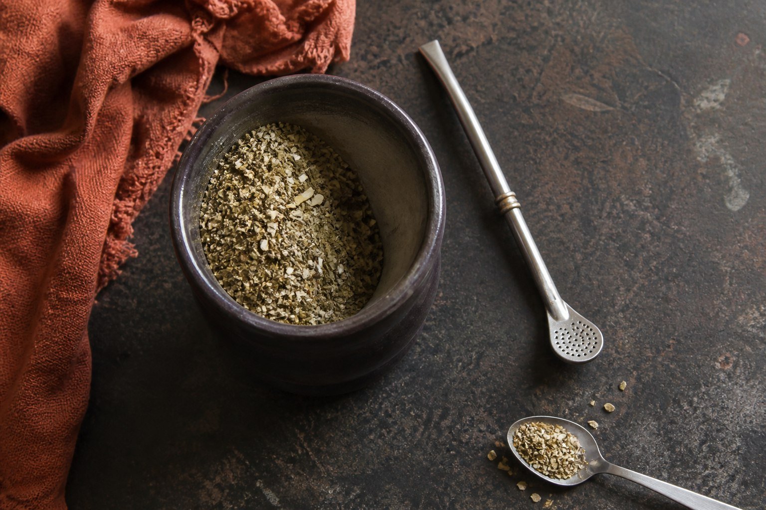 Loose yerba mate arranged in a sloped mound beside a bombilla before adding hot water.