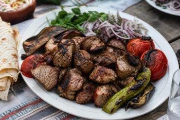 Armenian khorovats grilled pork with fire-roasted vegetables, onion, herbs, and lavash.